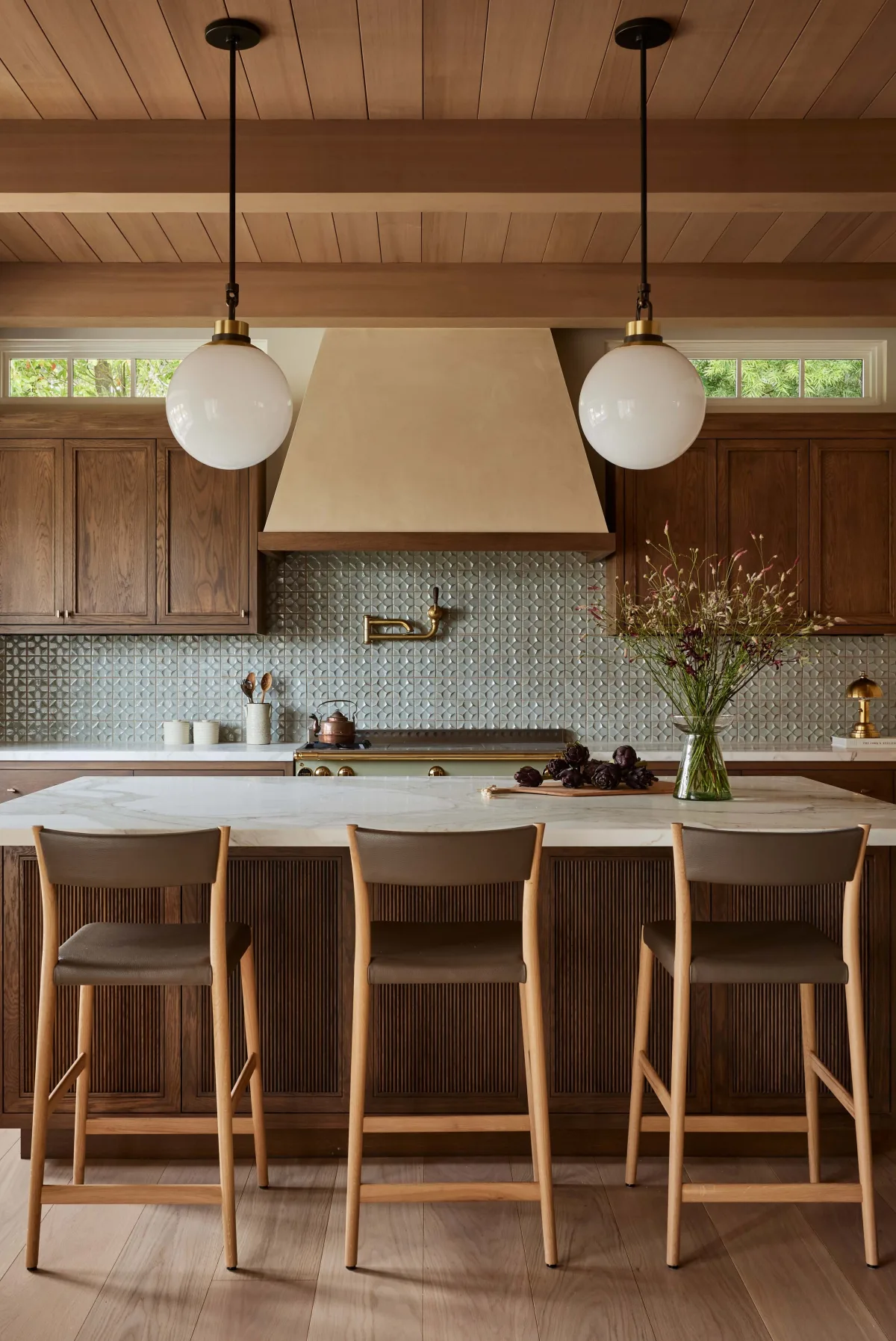 Kitchen with dark green island, brass hardware, and open shelving